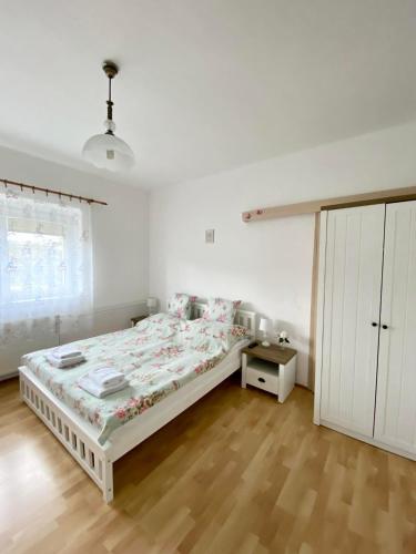 a white bedroom with a bed and a wooden floor at Apartmán Markéta in Bystrzyca