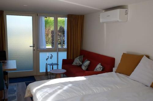 a bedroom with a bed and a red couch at Dajan in Almere