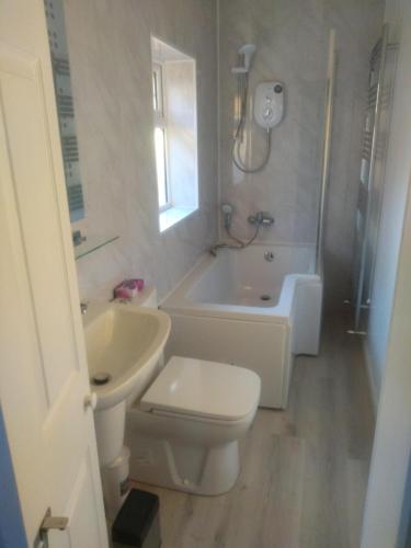 a bathroom with a toilet and a tub and a sink at Cheltenham - 3 Bed Newly Renovated With Parking in Cheltenham