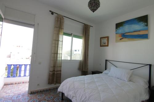 1 dormitorio con cama y ventana grande en zina surf house en Oualidia