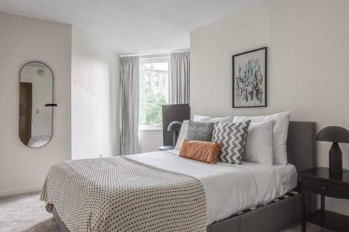 a white bedroom with a large bed with a mirror at BackBay Center Lux 2BR 2BA condo in Boston