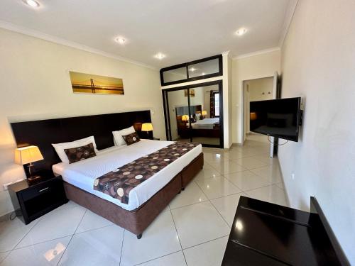 a bedroom with a large bed and a flat screen tv at Hotel Fatima in Tete
