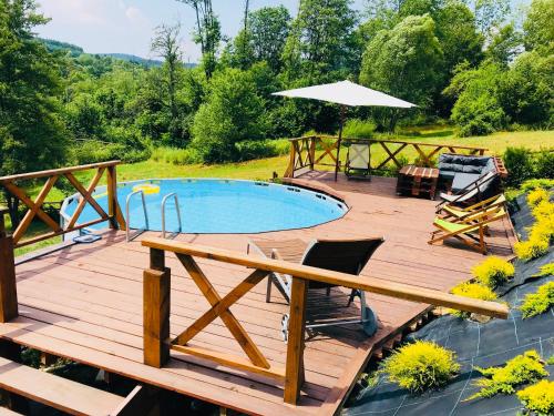 a wooden deck with a swimming pool and an umbrella at Tarninowe Wzgórze in Kunkowa