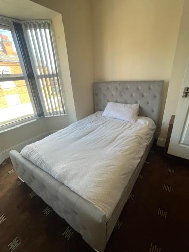 a bed in a room with a bed frame and two windows at 1 Bedroom Flat - Milligan Road Leicester in Leicester