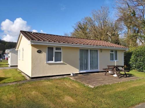 a small house with a picnic table in the yard at Light and bright 3 bedroom bungalow in Cornwall in Liskeard