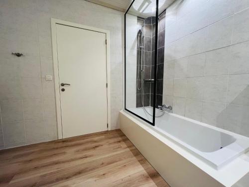 a bathroom with a bath tub and a glass door at Ruim app. met grote garage in Ypres