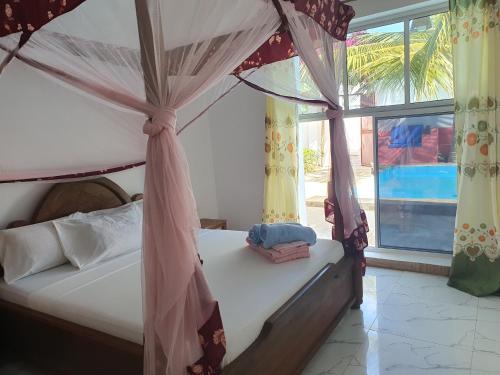 a bedroom with a canopy bed and a window at BARIDI VILLA in Kiwengwa