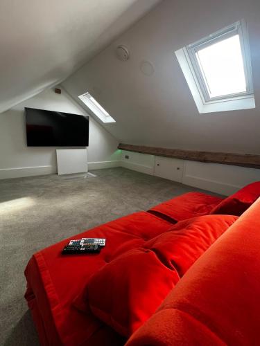 a room with a red couch and a flat screen tv at Modern Townhouse in the heart of Beaumaris in Beaumaris