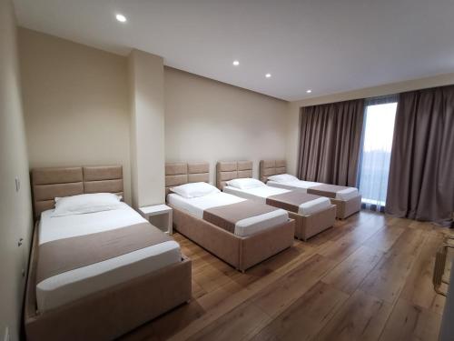 three beds in a room with wooden floors at Te Aldo Hotel in Durrës