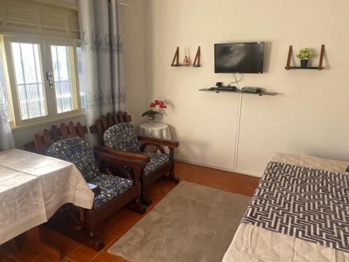 a dining room with chairs and a tv on the wall at Pousada Apartamento loft Braga in Cabo Frio