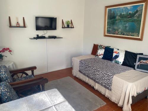 a room with two beds and a tv on the wall at Pousada Apartamento loft Braga in Cabo Frio