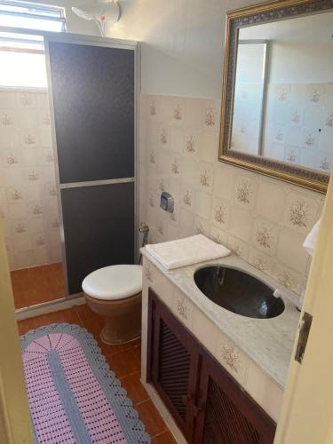 a bathroom with a sink and a toilet and a mirror at Pousada Apartamento loft Braga in Cabo Frio