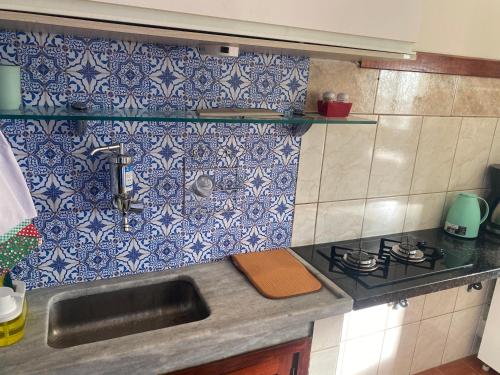 a kitchen with a sink and blue and white tiles at Pousada Apartamento loft Braga in Cabo Frio