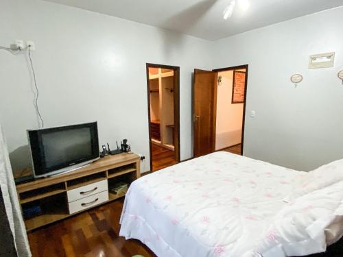 a bedroom with a bed and a flat screen tv at Casa confortável com churrasqueira na Granja Viana in Carapicuíba