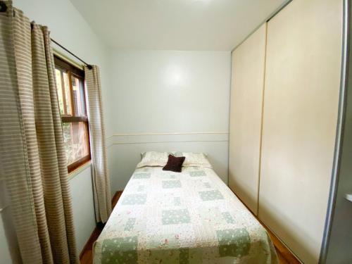 a small bedroom with a bed with a quilt on it at Casa confortável com churrasqueira na Granja Viana in Carapicuíba