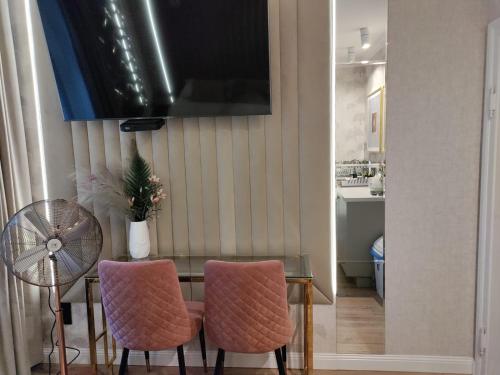 a dining room with a table and two pink chairs at StayCity - starówka Zielona Góra in Zielona Góra