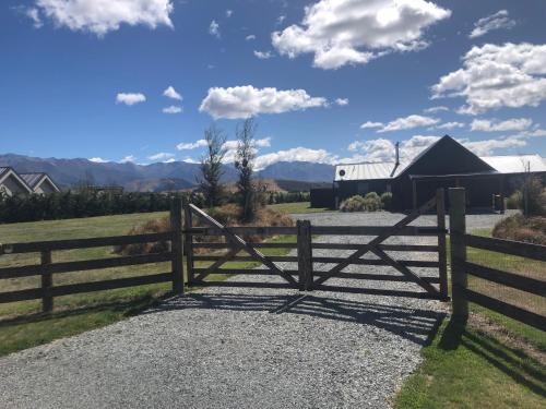 a gate to a pasture with mountains in the background at Antlers Rest - Twizel in Twizel