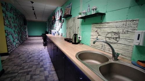 ein Badezimmer mit einem Waschbecken und grünen Wänden in der Unterkunft Міні Готель "БУНКЕР" на Солом'янському in Kiew