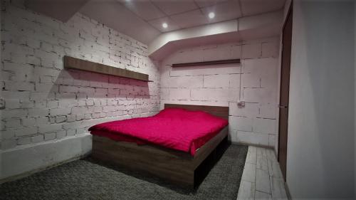 a bedroom with a red bed in a brick wall at Міні Готель "БУНКЕР" на Солом'янському in Kyiv