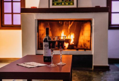 a bottle of wine and two glasses on a table in front of a fireplace at Refúgio com piscina e churrasqueira in Sao Paulo