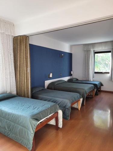 three beds in a room with blue walls at Hotel Brasil in São Lourenço
