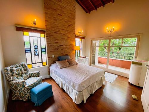 a bedroom with a bed and a chair and windows at Piscina aquecida, lareira e vista cinematográfica in Carapicuíba