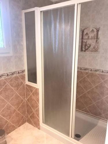 une douche avec une porte vitrée dans une salle de bain dans l'établissement Grand appartement 3 chambres avec garage, à Lapalme
