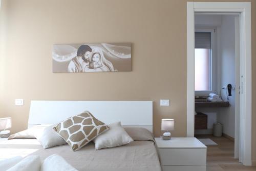ein Schlafzimmer mit einem weißen Bett mit einem Bild an der Wand in der Unterkunft Casa Agorà in Cefalú