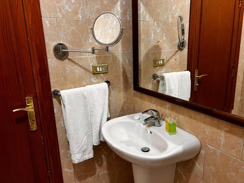 y baño con lavabo, espejo y toallas. en Twilight Hotel Petra, en Wadi Musa