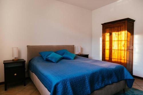 a bedroom with a bed with blue sheets and a window at Casa villetta "La Colomba" Nizza Monferrato in Nizza Monferrato