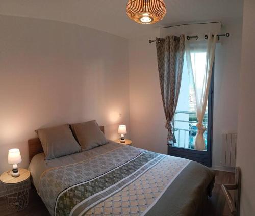 um quarto com uma cama com 2 candeeiros e uma janela em Cosy appartement avec vue sur Genève em Collonges-sous-Salève