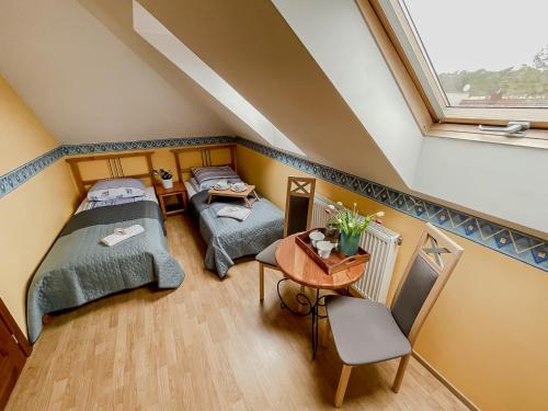 Pokój na poddaszu z 2 łóżkami i stołem w obiekcie Fiord w Łebie