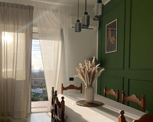 ein grünes Esszimmer mit einem Tisch und einem Fenster in der Unterkunft Kesya Seaview Apartment - Attico - 50mt dal mare in Anzio