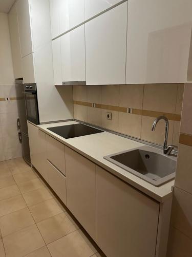 a kitchen with white cabinets and a sink at Great location two bedroom apatment ''MAXIM'' in Podgorica