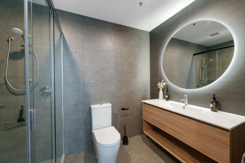y baño con aseo, lavabo y espejo. en Executive Oceanside Apartment, en Mount Maunganui