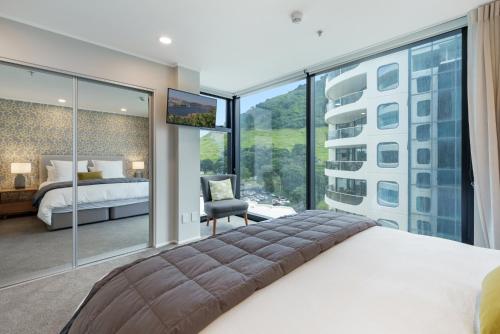 a bedroom with a bed and a large window at Executive Oceanside Apartment in Mount Maunganui