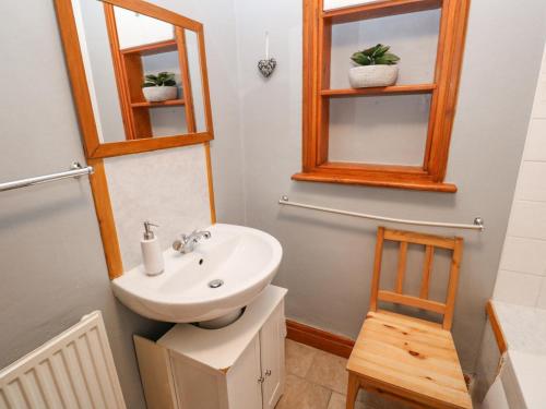 a bathroom with a sink and a mirror and a chair at Trelydarth in St. Agnes 