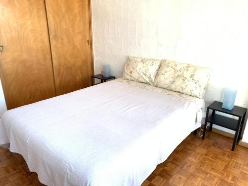 a bedroom with a white bed with two night stands at Casa na Praia in Sesimbra
