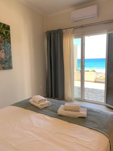 a bedroom with a bed with a view of the ocean at Nereides Suites in Agios Gordios