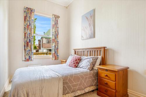 um quarto com uma cama com uma cómoda e uma janela em 4Bed Spacious Villa in Chatswood em Auckland