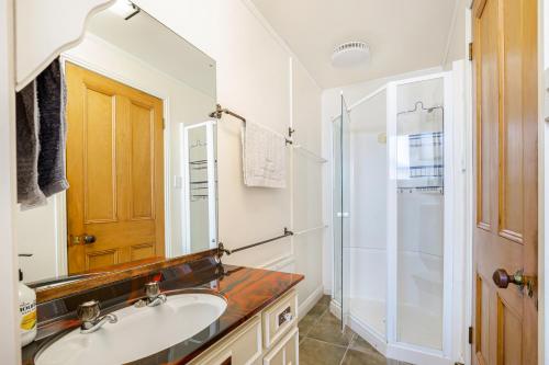 uma casa de banho com um lavatório e um chuveiro em 4Bed Spacious Villa in Chatswood em Auckland