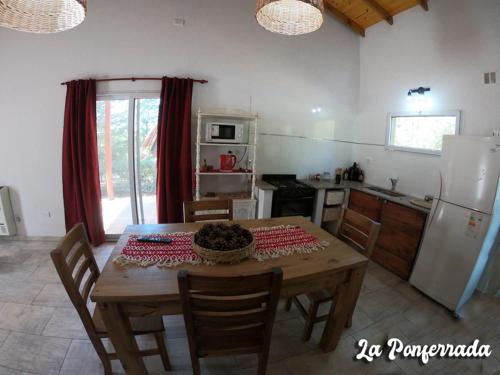 cocina con mesa de madera y nevera en La ponferrada en Villa Ventana