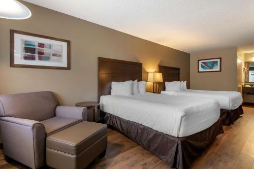 a hotel room with two beds and a chair at SureStay Plus Hotel by Best Western Salmon Arm in Salmon Arm
