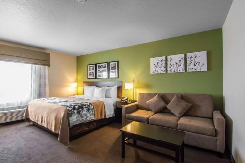 Sleep Inn Regina East في ريجينا: غرفه فندقيه بسرير واريكه