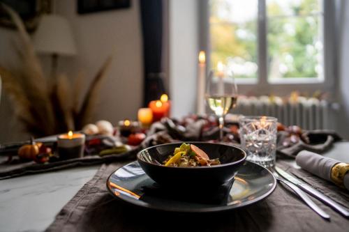 a table with a bowl of food and a glass of wine at Chateau des Ayes - Chambres & suites in Saint-Étienne-de-Saint-Geoirs