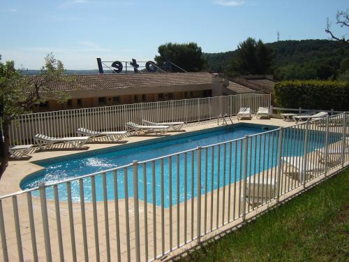 une clôture autour d'une piscine avec des chaises dans l'établissement Logis Hotel Le Col De L'ange, à Draguignan