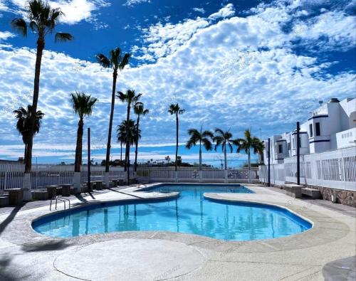 une piscine avec des palmiers et un ciel bleu dans l'établissement Condominio 231 Loma Bonita, enfrente de la alberca!, à San Carlos
