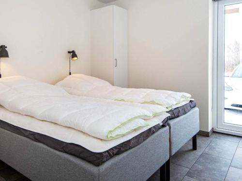 ein Bett mit weißer Bettwäsche auf einem Zimmer in der Unterkunft Holiday home Ringkøbing LXXX in Ringkøbing