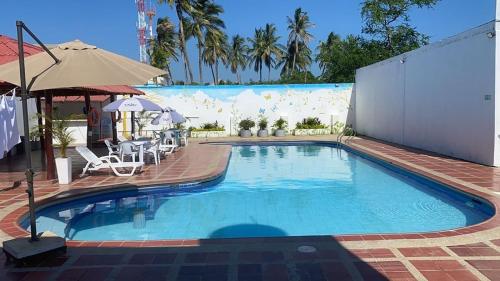 a large swimming pool with chairs and an umbrella at Hotel la Sierra Riohacha II in Ríohacha