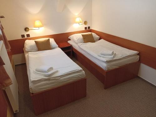 Dos camas en una habitación de hotel con toallas. en Penzion U Halířů, en Mladé Buky